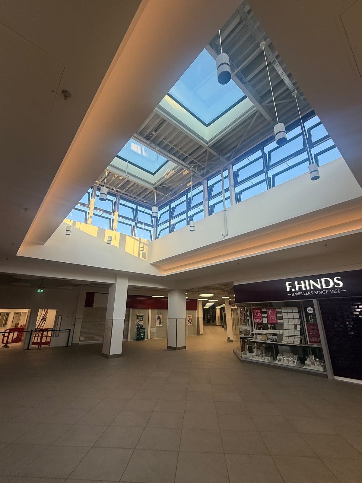 Pendant lights hung under a glazed atrium roof in a shopping centre
